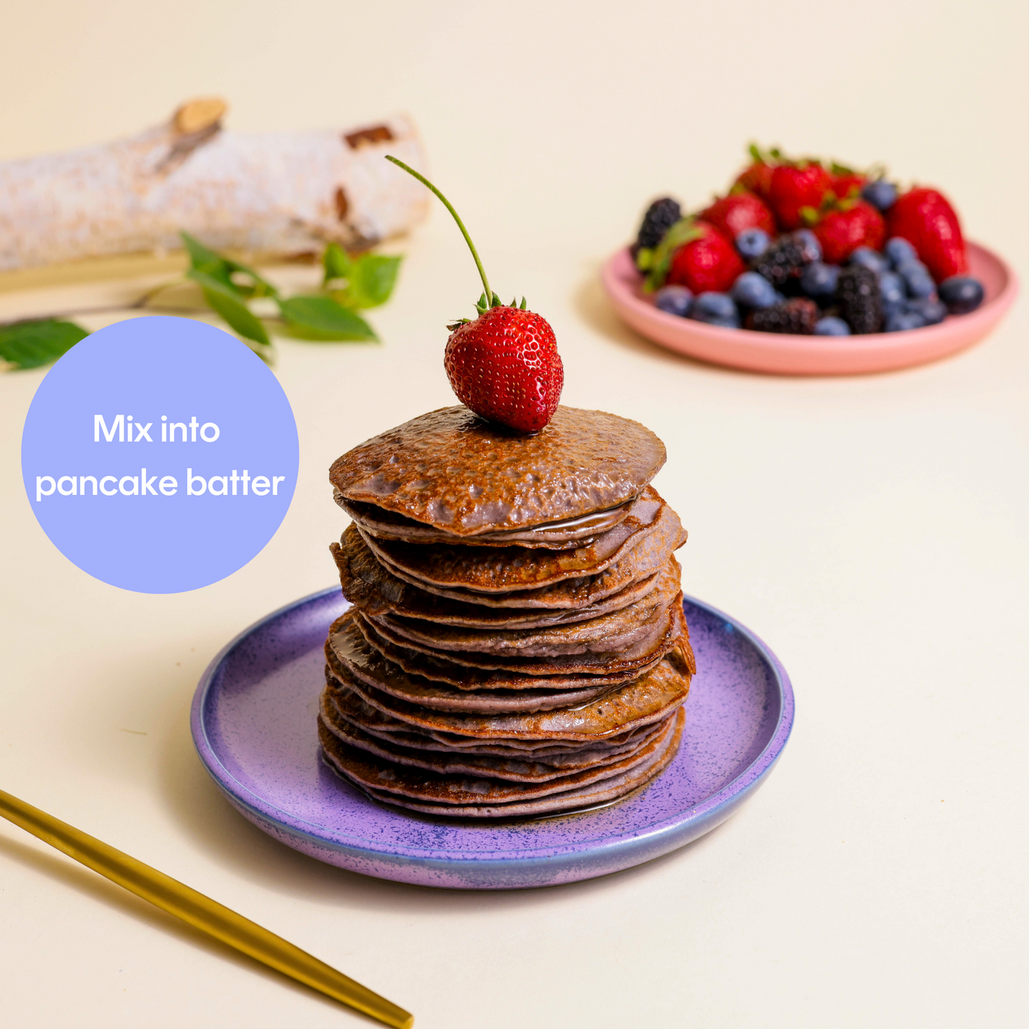 Stack of pancakes with a plate of berries in the background